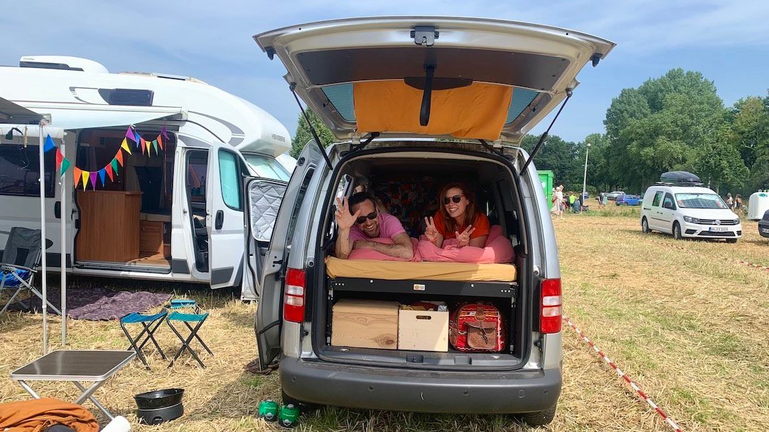 Zwei menschen liegen in einem Caddy auf einem Festivalgelände.