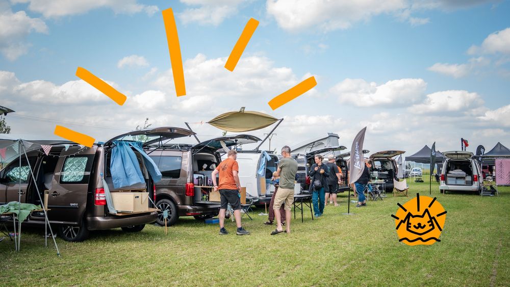 Mehrere selbst ausgebaute Caddys stehen auf einer Wiese im Festivalambiente.