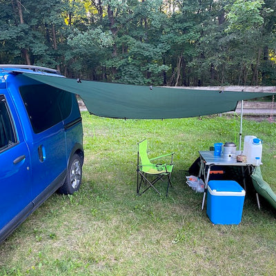 Ein Minicamper steht mit Vorzelt auf einer Wiese.